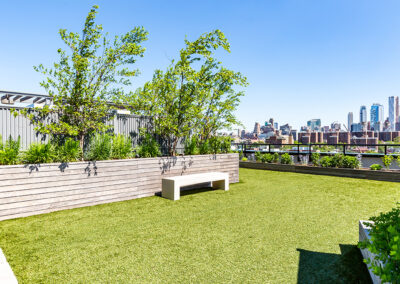 Rooftop green area with bench, plants, and a city view at 363 Bond Street apartments.