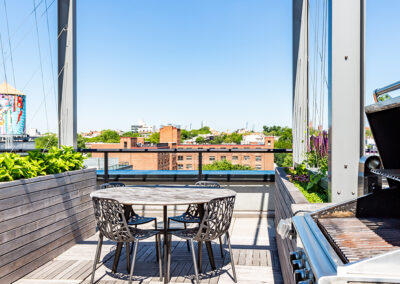 Rooftop lounge area with cabana, seating area, and outdoor grill on a sunny day.