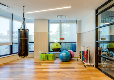 Indoor yoga studio with boxing and yoga equipment on hardwood floors.